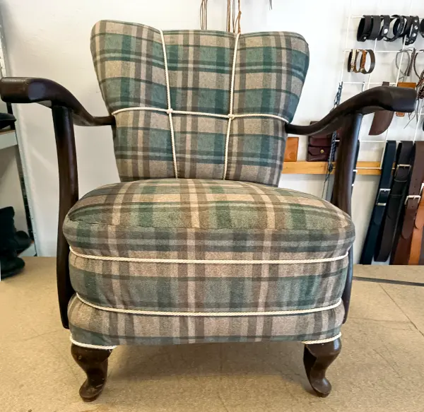 Starobylé křeslo po renovaci s novým károvaným látkovým čalouněním a ozdobným provazem.