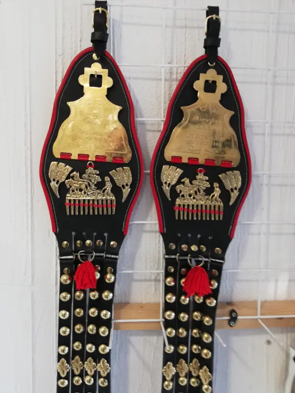 Dvojice bohatě zdobených kožených závěsů na chomout s mosazným kováním