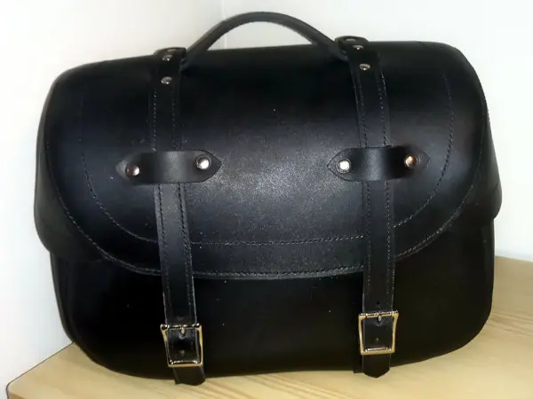 Čelní pohled na minimalistickou černou koženou brašnu s přezkami