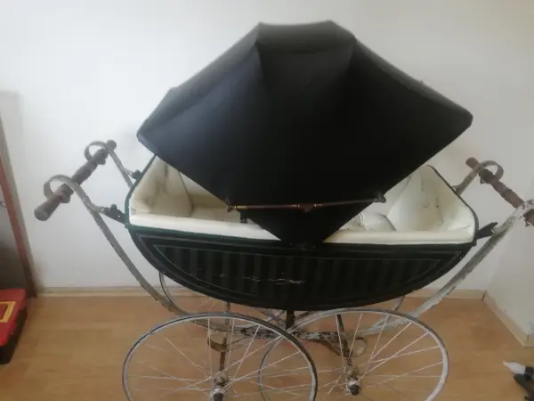 Zrenovovaný historický kočárek s černou střechou a světlým vnitřkem